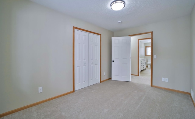 unfurnished bedroom with a closet, baseboards, light colored carpet, and a textured ceiling