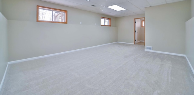 below grade area featuring carpet flooring, baseboards, visible vents, and a drop ceiling