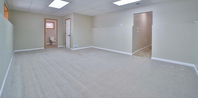 spare room with a drop ceiling, baseboards, carpet, and visible vents