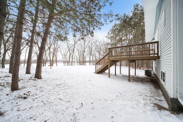 yard covered in snow featuring cooling unit, a wooden deck, and stairway