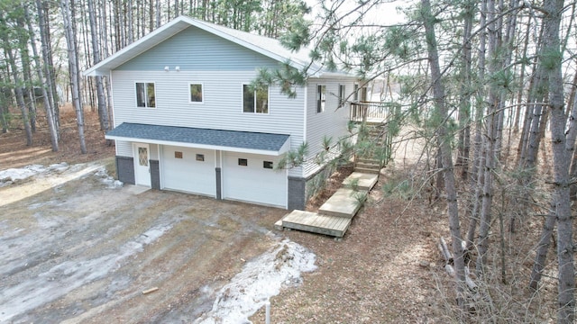 exterior space featuring a garage, driveway, and roof with shingles