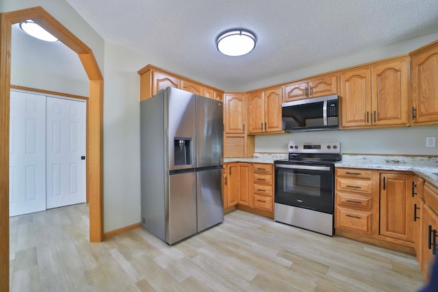 1505 Harrison Dr SW, Brainerd, MN 56401 - kitchen featuring stainless steel appliances, light wood-type flooring, a textured ceiling, light stone countertops, and brown cabinetry