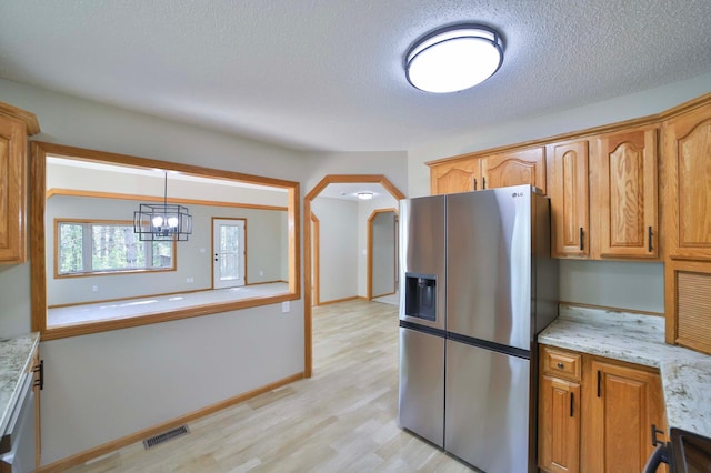 1505 Harrison Dr SW, Brainerd, MN 56401 - kitchen featuring stainless steel fridge, light wood-style flooring, a textured ceiling, arched walkways, and light stone counters