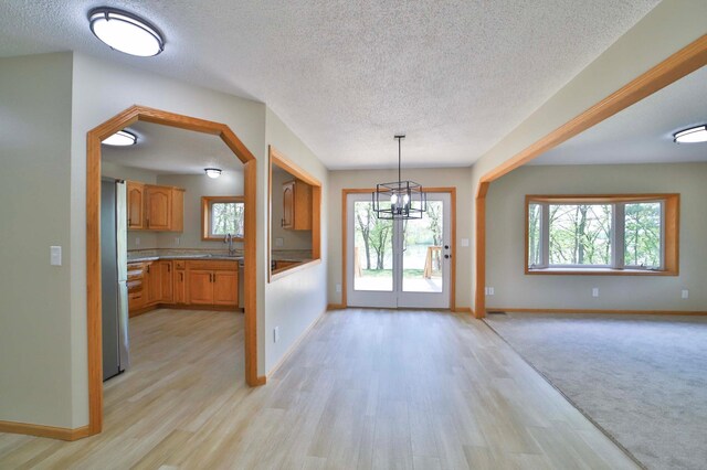 1505 Harrison Dr SW, Brainerd, MN 56401 - unfurnished dining area with a textured ceiling, baseboards, light wood-style flooring, and healthy amount of natural light