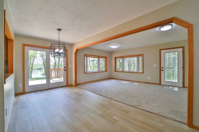 1505 Harrison Dr SW, Brainerd, MN 56401 - unfurnished dining area with light wood-type flooring, a chandelier, baseboards, and a textured ceiling