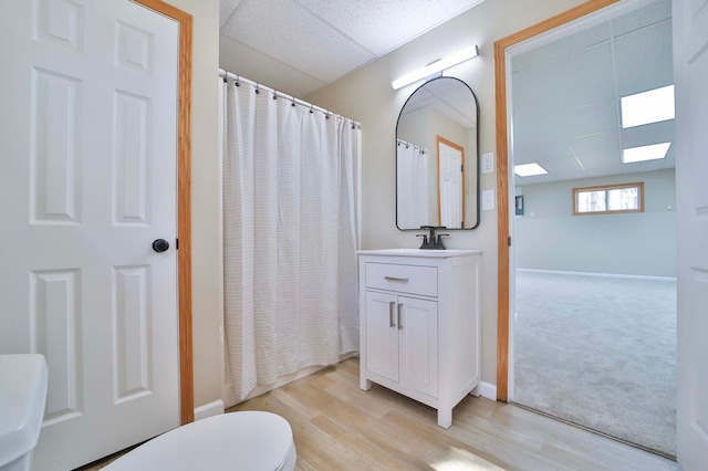 1505 Harrison Dr SW, Brainerd, MN 56401 - full bathroom with toilet, wood finished floors, vanity, baseboards, and a paneled ceiling