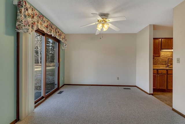 spare room featuring carpet floors, a textured ceiling, visible vents, and a sink