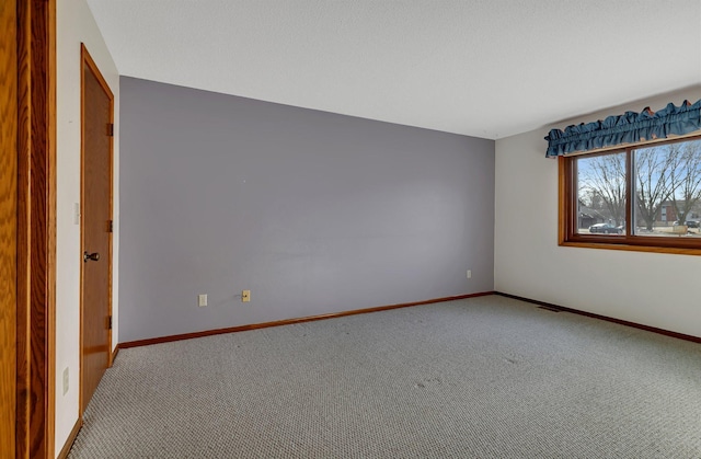 carpeted spare room with visible vents and baseboards