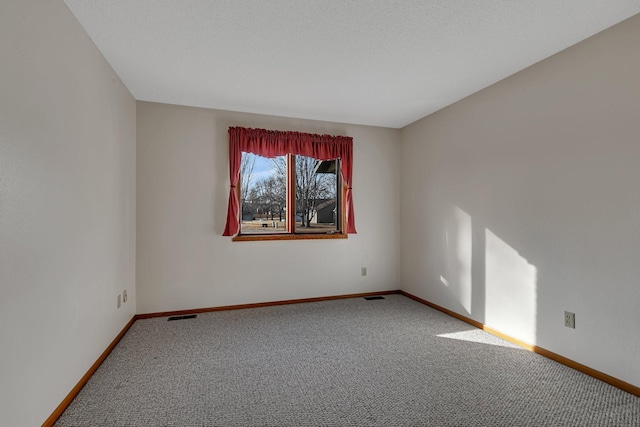 unfurnished room featuring baseboards, visible vents, and carpet flooring