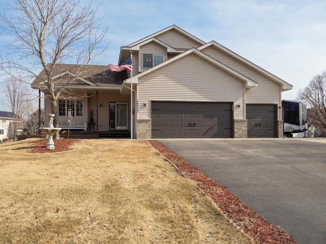 view of front facade with aphalt driveway, covered porch, brick siding, and an attached garage