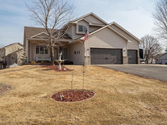 traditional-style house with aphalt driveway, covered porch, brick siding, and a front lawn