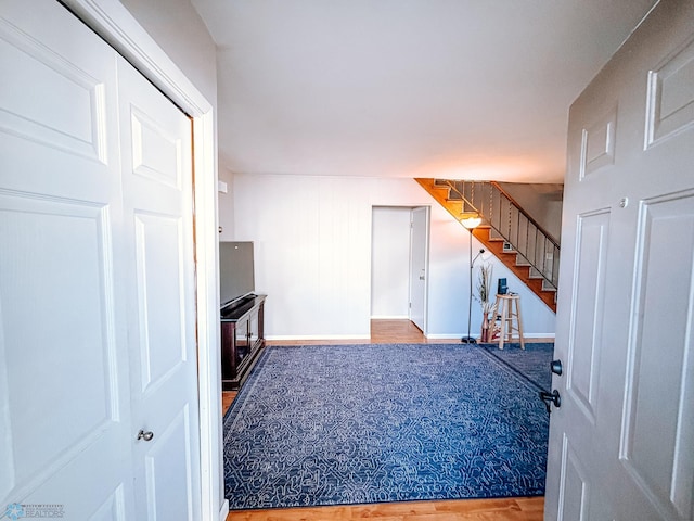 unfurnished living room featuring wood finished floors, baseboards, and stairs