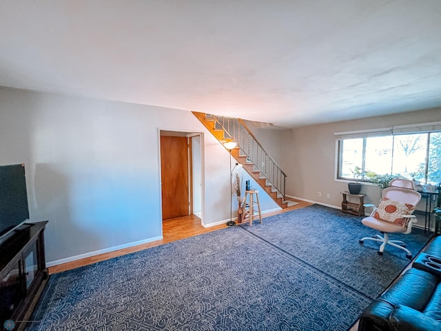 unfurnished living room with stairs, baseboards, and wood finished floors