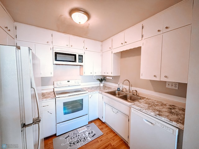 kitchen with light wood-style flooring, white appliances, a sink, white cabinets, and light countertops