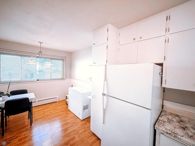 kitchen featuring white cabinets, light countertops, baseboard heating, light wood-type flooring, and freestanding refrigerator