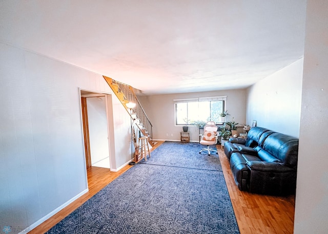 living area featuring baseboards, stairway, and wood finished floors