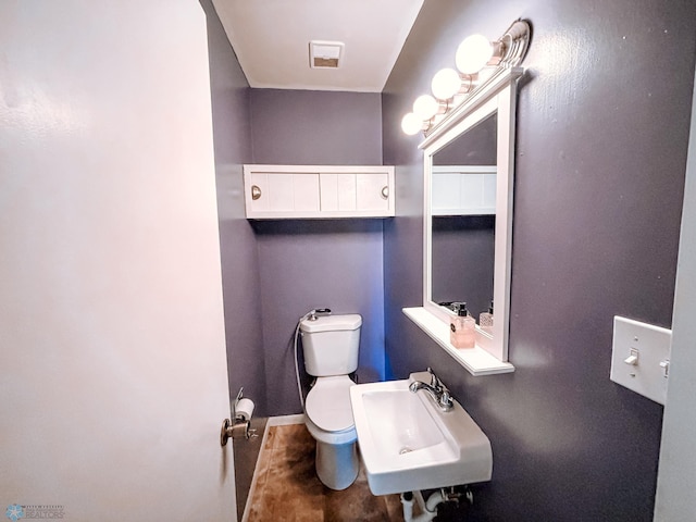 half bathroom with visible vents, a sink, toilet, and baseboards