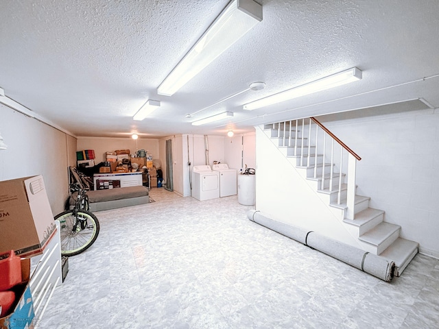 finished below grade area with concrete block wall, washing machine and clothes dryer, stairway, a textured ceiling, and tile patterned floors