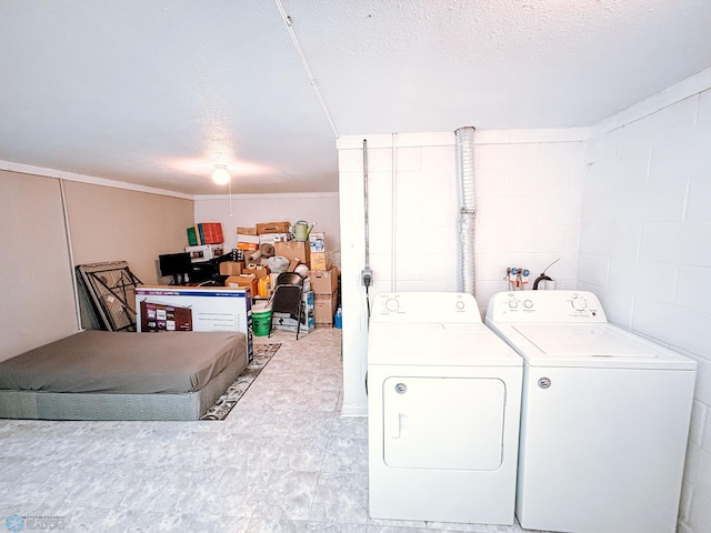 washroom with concrete block wall, laundry area, a textured ceiling, and washer and dryer