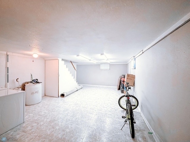 below grade area with a textured ceiling, baseboards, tile patterned floors, washer / clothes dryer, and concrete block wall