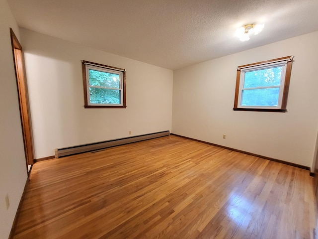 13857 Jacob Ave, Nininger Twp, MN 55033 - empty room with a baseboard heating unit, light wood-style floors, and a textured ceiling