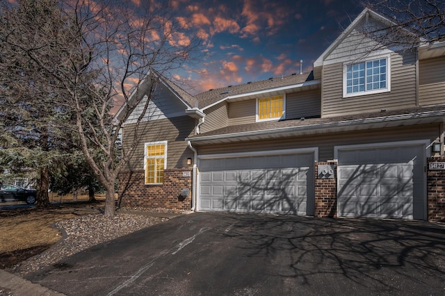 view of front of property featuring a garage, brick siding, and aphalt driveway