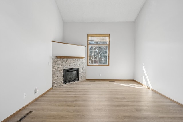 unfurnished living room featuring baseboards, a fireplace, visible vents, and wood finished floors