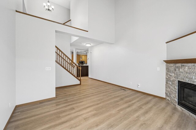 unfurnished living room featuring stairway, a fireplace, wood finished floors, and baseboards