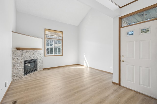 unfurnished living room featuring baseboards, vaulted ceiling, wood finished floors, and a glass covered fireplace