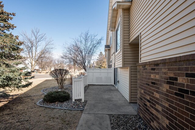 view of side of property featuring brick siding and fence