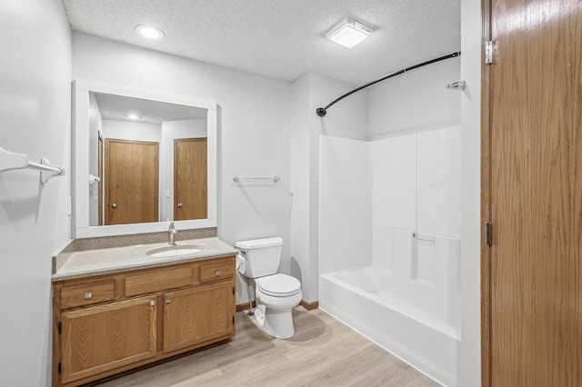 full bathroom with a textured ceiling, bathtub / shower combination, toilet, wood finished floors, and vanity