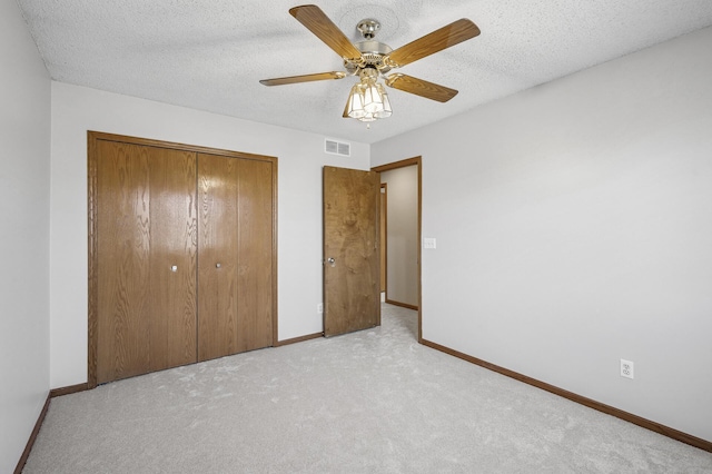 unfurnished bedroom featuring a closet, visible vents, light carpet, a textured ceiling, and baseboards