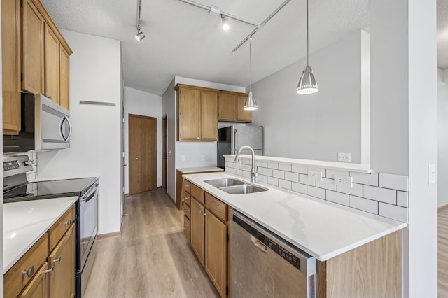 kitchen featuring stainless steel appliances, a sink, light countertops, light wood-type flooring, and tasteful backsplash