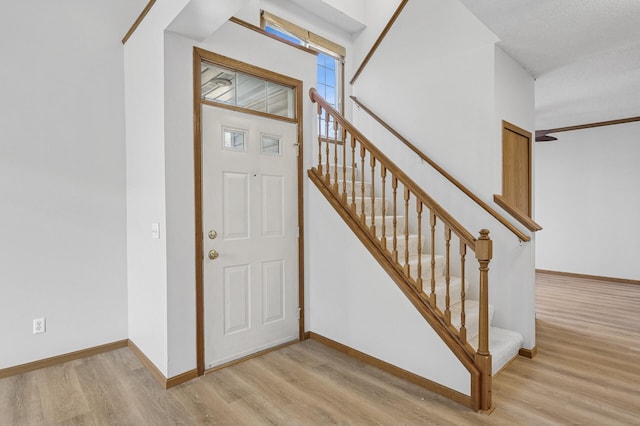 foyer entrance with stairway, baseboards, and wood finished floors