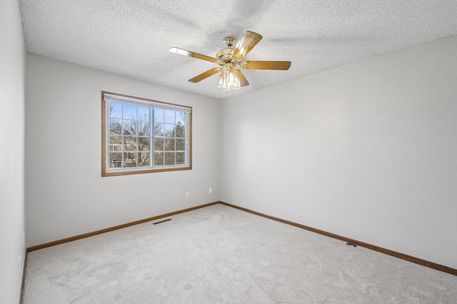 carpeted spare room with baseboards, a textured ceiling, visible vents, and a ceiling fan