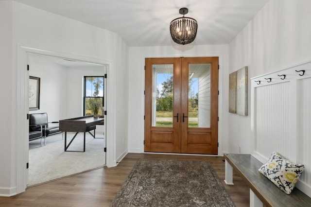 foyer entrance with french doors, an inviting chandelier, and wood finished floors