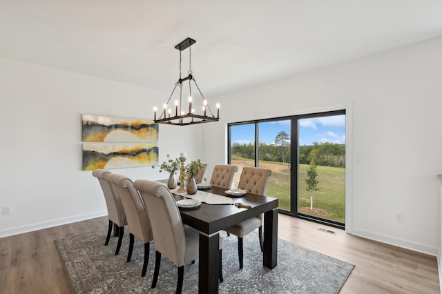 dining area featuring visible vents, baseboards, an inviting chandelier, and wood finished floors