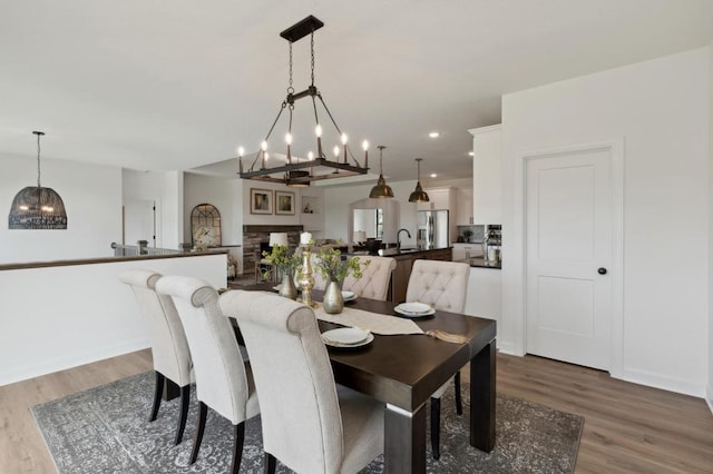 dining room featuring wood finished floors, recessed lighting, a fireplace with raised hearth, and baseboards