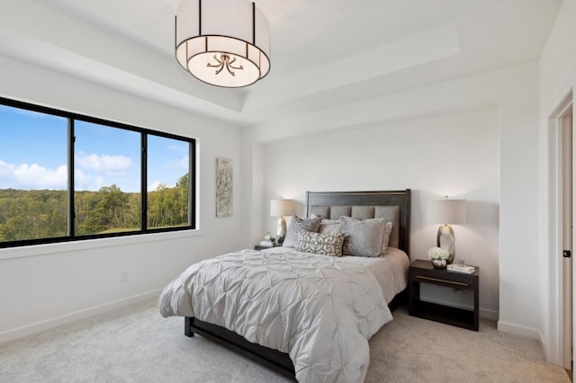 carpeted bedroom featuring baseboards and a tray ceiling