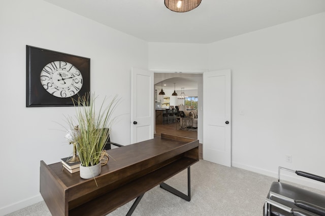 home office with baseboards and light carpet