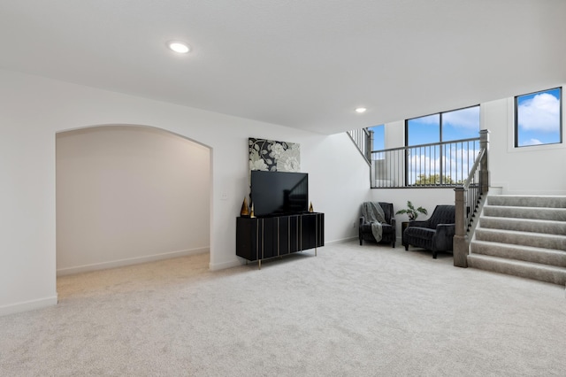 living room featuring baseboards, carpet, stairs, recessed lighting, and arched walkways