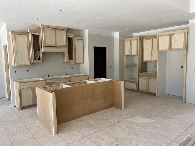 kitchen with a kitchen island, light brown cabinetry, a textured ceiling, and recessed lighting