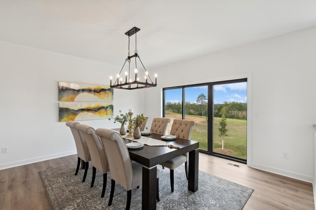 dining space with a chandelier, wood finished floors, and baseboards