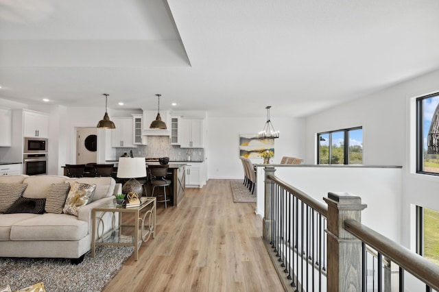 living area with light wood-style flooring, recessed lighting, and a chandelier