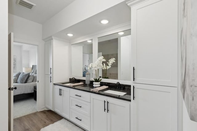 ensuite bathroom featuring wood finished floors, double vanity, and recessed lighting