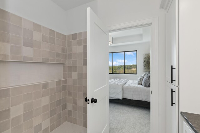 full bathroom featuring a tile shower and ensuite bathroom