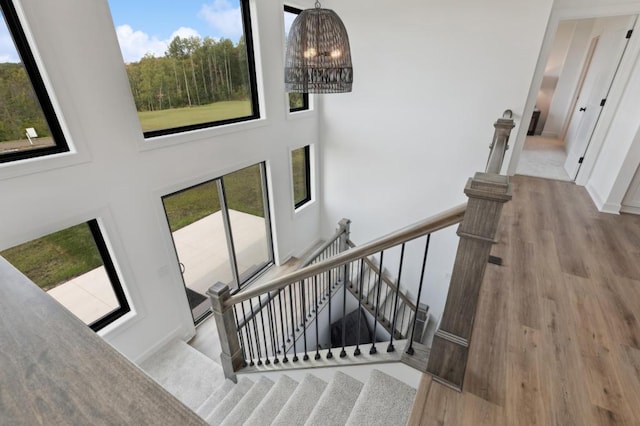 staircase featuring wood finished floors, a chandelier, and a towering ceiling