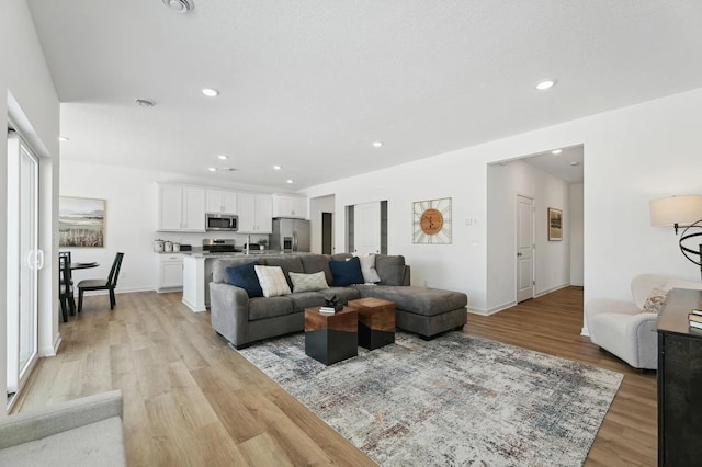 living area with recessed lighting, light wood-style floors, and baseboards