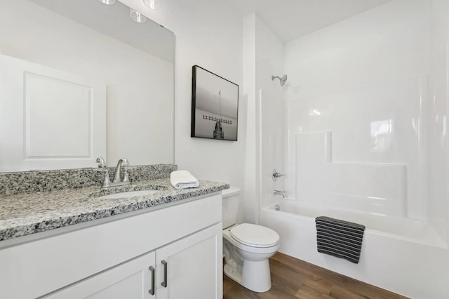 bathroom with washtub / shower combination, toilet, vanity, and wood finished floors