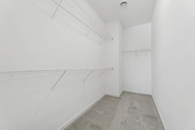 spacious closet with light colored carpet and visible vents